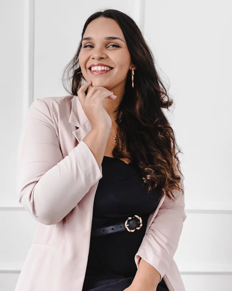 Jéssica Borowsky sorrindo, de blazer rosa, com a mão no queixo